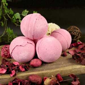 Des bombes de bain Cranberry disposées sur un plateau en bois. Elles sont d'un beau rose vif.